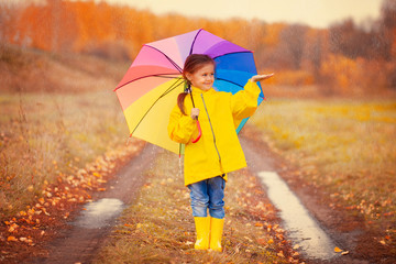 Happy kid catches raindrops in autumn park
