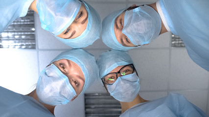 Smiling surgeon team faces, pov patient waking up after operation anesthesia - obrazy, fototapety, plakaty