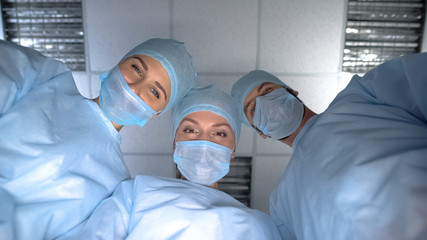 Pov patient waking up after operation anesthesia, smiling surgeon team faces