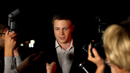 Producer giving interview to paparazzi answering questions about successful film