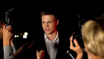 Handsome actor giving interview on press conference before movie premier, fame