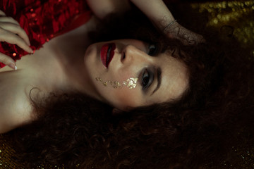 femininity, beautiful redhead woman with curly and lush hair with tears of gold leaf in the style of the painter Klimt