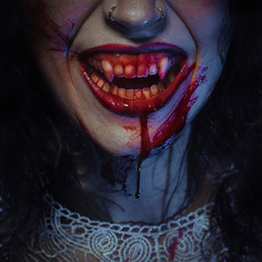 Vampire smile demon woman laughing with big fangs full of blood, image for halloween