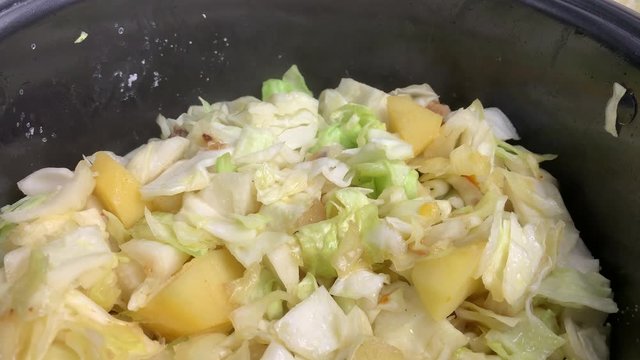The chef is preparing bigos - a Polish dish of meat, potatoes and cabbage. Close-up