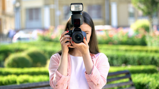 Female photographer taking photos with camera in park, lessons for beginners