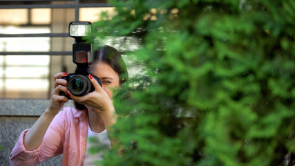 Female paparazzi hiding behind trees taking photos, searching for sensation