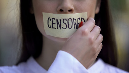 Woman taking off tape with censored word over mouth, democracy concept, freedom