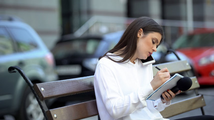 Female journalist making notes and talking phone, preparing for reportage