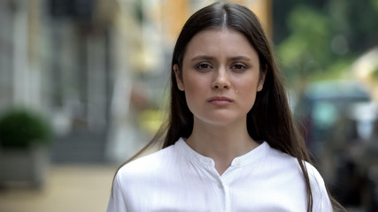 Depressed woman crying on city street, looking at camera, boyfriend betrayal