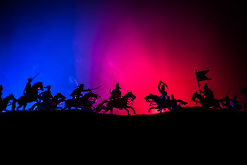 Naklejka na ściany i meble Medieval battle scene with cavalry and infantry. Silhouettes of figures as separate objects, fight between warriors on dark toned foggy background. Night scene.