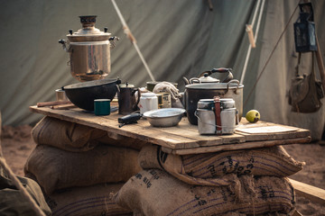military field kitchen. Wooden table with various appliances in the form of a samovar, cauldron,...
