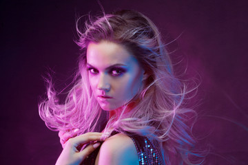 Young attractive blonde woman dancing in club, color light, motion effects