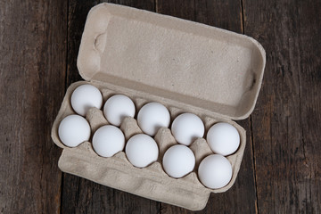 white chicken eggs in a cardboard box on wooden table