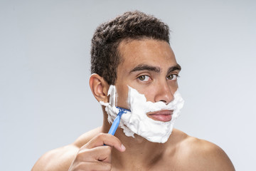 Calm young man shaving in the morning