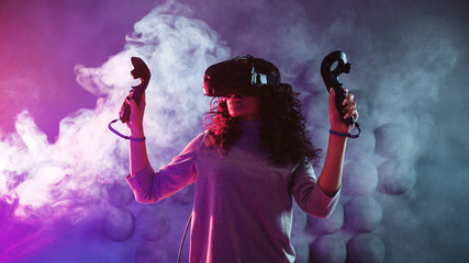 Virtual reality game. A girl in a VR helmet plays a game or explores the environment. © Ulia Koltyrina