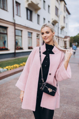 Fashionable beautiful young blondie woman posing in trendy fashionable coat outdoors. Beauty,...