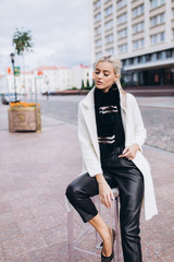 Fashionable beautiful young blondie woman posing in trendy fashionable coat outdoors. Beauty,...