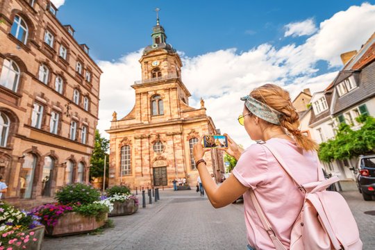 A girl traveler taking photo of the St John Baptist Church in Saarbrücken. Travel in Germany concept