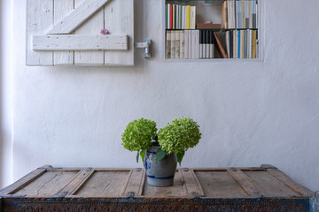 Closeup highboy with vase and flowers and bookshelf with shutter