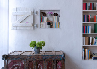 Beautiful rustic interieur with cabinet flowers and bookshelf  with shutter in white wall