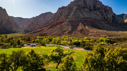 Fototapeta na wymiar Beautiful view of famous Spring Mountain Ranch State Park near Las Vegas and Red Rock Canyon, Nevada during autumn with pink and red rock mountains, blue sky, green trees and grass, and purple hills