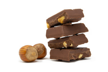 pieces of chocolate one on top of the other and hazelnuts on a white background macro photography