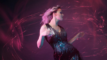 Attractive dancing blonde in the club, neon light, motion effects