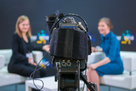 Television Video Camera Recording Interview In Broadcast News Studio. Blurred Background. Media, Production, TV And Broadcast Concept