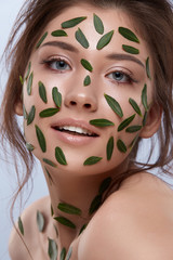 fresh female face with leaves and natural make-up
