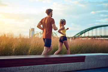 Modern woman and man jogging / exercising in urban surroundings near the river.