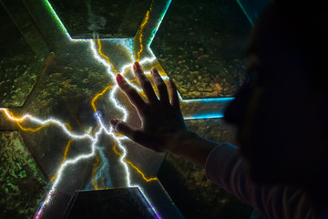 Woman hand touching plasma panel display. Interactive touchscreen exposition in science museum. Electricity, education, science, futuristic and physics concept