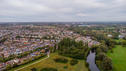 An aerial view of an urban area along a park under a grey sky and white clouds