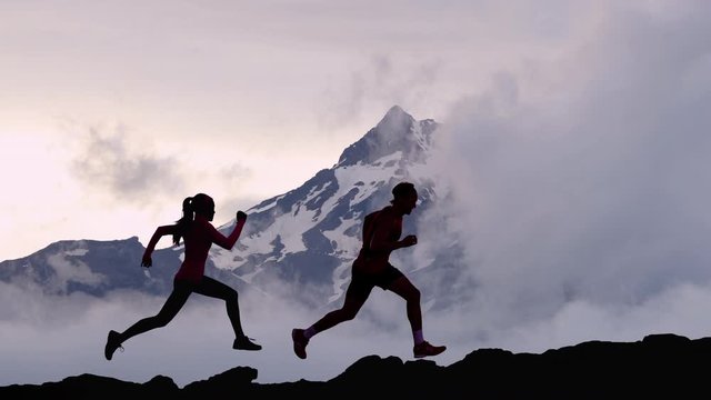 CINEMAGRAPH - seamless loop video. Running people athletes silhouette trail running in mountain summit background. Man and woman on run training outdoors active fit lifestyle. Looping Motion photo.