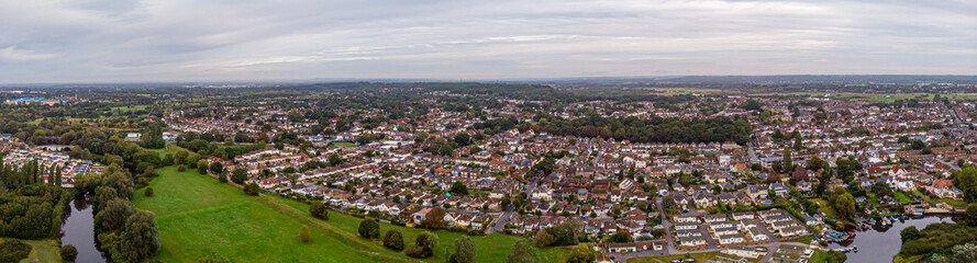 An aerial view of an urban area along a park and river under a grey sky and white clouds