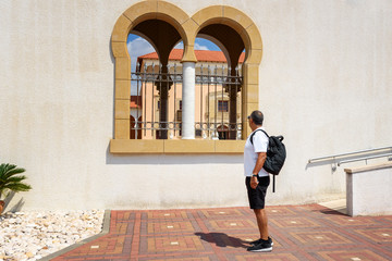 Energetic Elderly Tourist Man Walking With Backpack In City. Portrait Of Business Confident Senior Traveler Man On Vacation. Travel And Tourism Concept.