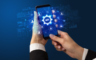 Female hand holding smartphone with API abbreviation, modern technology concept