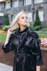 Fashionable beautiful young blondie woman posing in trendy fashionable coat outdoors. Beauty,...