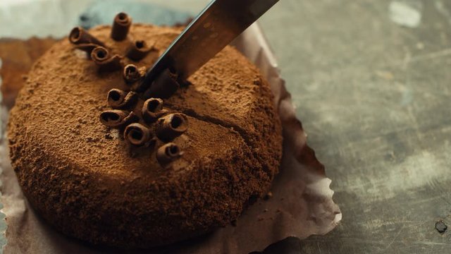 Closeup hands cutting cake in slow motion. Macro of knife cutting chocolate cake
