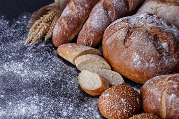 Bakery - gold rustic crusty loaves of bread and buns on black chalkboard background.