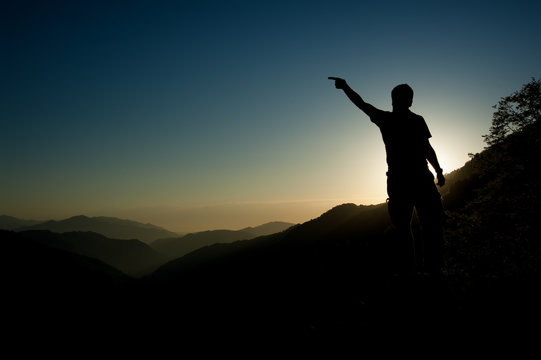 silhouette of man on top of mountain