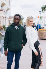 Happy interracial couple, black man and white woman walking in the city
