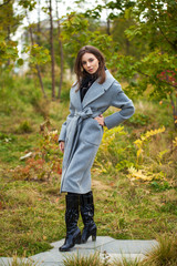 Portrait of young beautiful woman in gray coat posing in autumn park in Moscow