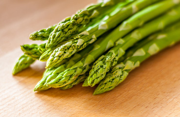 Bunch of green asparagus on a wooden board. Close-up with blured background.
