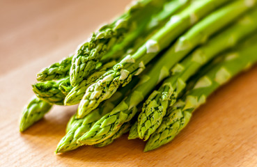 Bunch of green asparagus on a wooden board. Close-up with blured background.