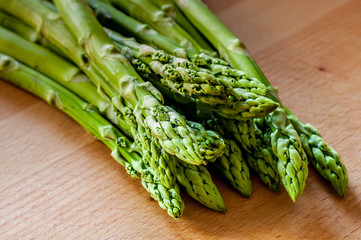 Bunch of green asparagus on a wooden board. (Close-up)