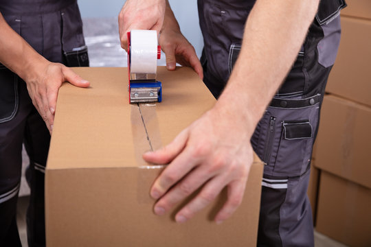 Young Men Packing Boxes To Move In New Flat