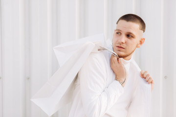 A stylish man wearing white after Black Friday shopping