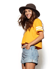 Portrait of smiling hipster girl in casual pretty clothes. Well-dressed model having fun in stylish hat. Brunette lovely lady on white background. Happiness and positivity concept