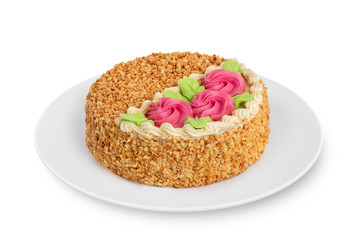 A round biscuit cake with cream lies on a white plate on a white background.
