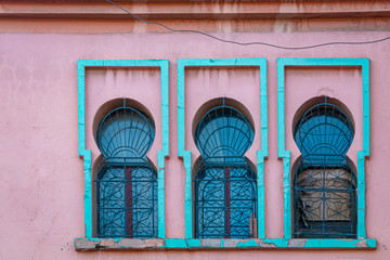 Fototapeta na wymiar Three windows with emerald green arch in pink wall. Morocco
